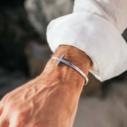 Cross bracelet worn on wrist with polished cuff band and raised cross detail