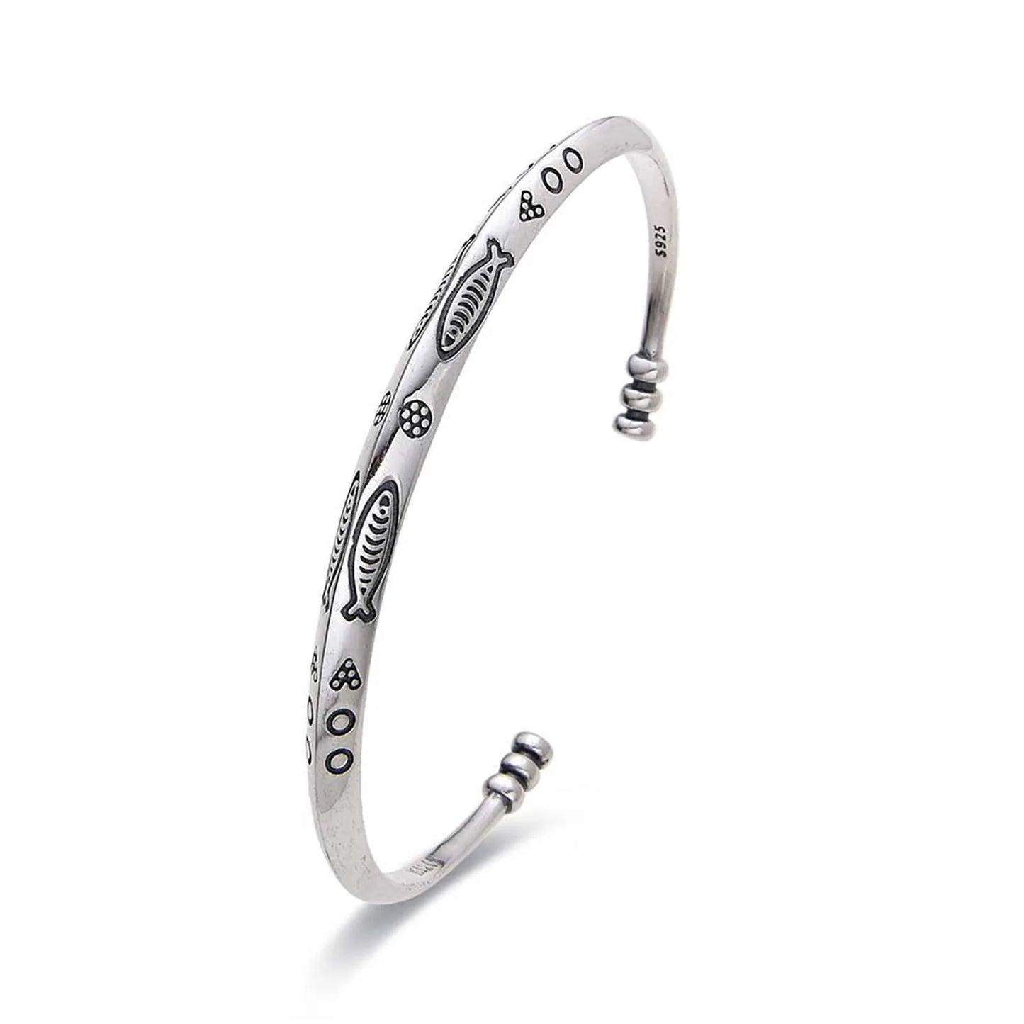 Cuff Bracelet shown in angled profile with fish engravings, dotted symbols, and rounded ends