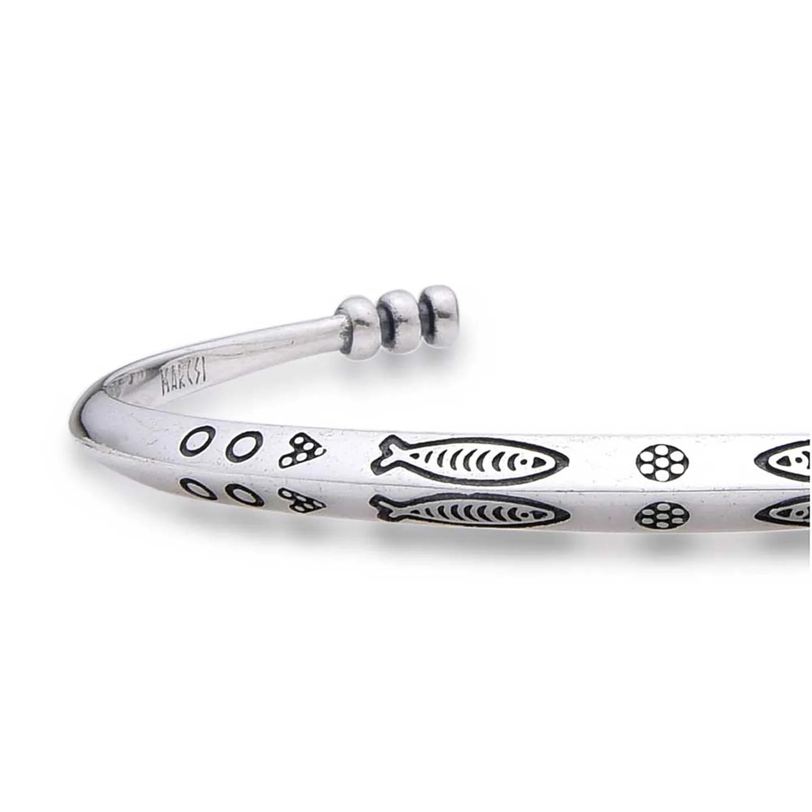 Close-up of Cuff Bracelet showing fish pattern, dotted engraving, and polished metal surface