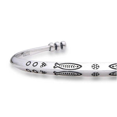 Close-up of Cuff Bracelet showing fish pattern, dotted engraving, and polished metal surface
