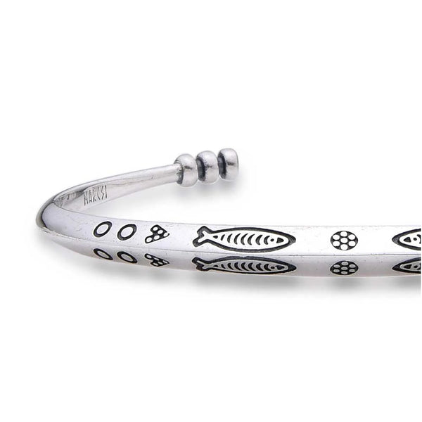 Close-up of Cuff Bracelet showing fish pattern, dotted engraving, and polished metal surface