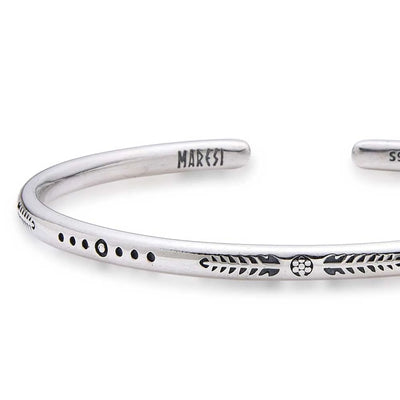 Close-up of Cuff Bracelet for Men with arrow, dot, and leaf engravings near branded end