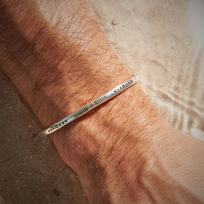 Lifestyle wrist view of Cuff Bracelet for Men with engraved symbols and open cuff fit