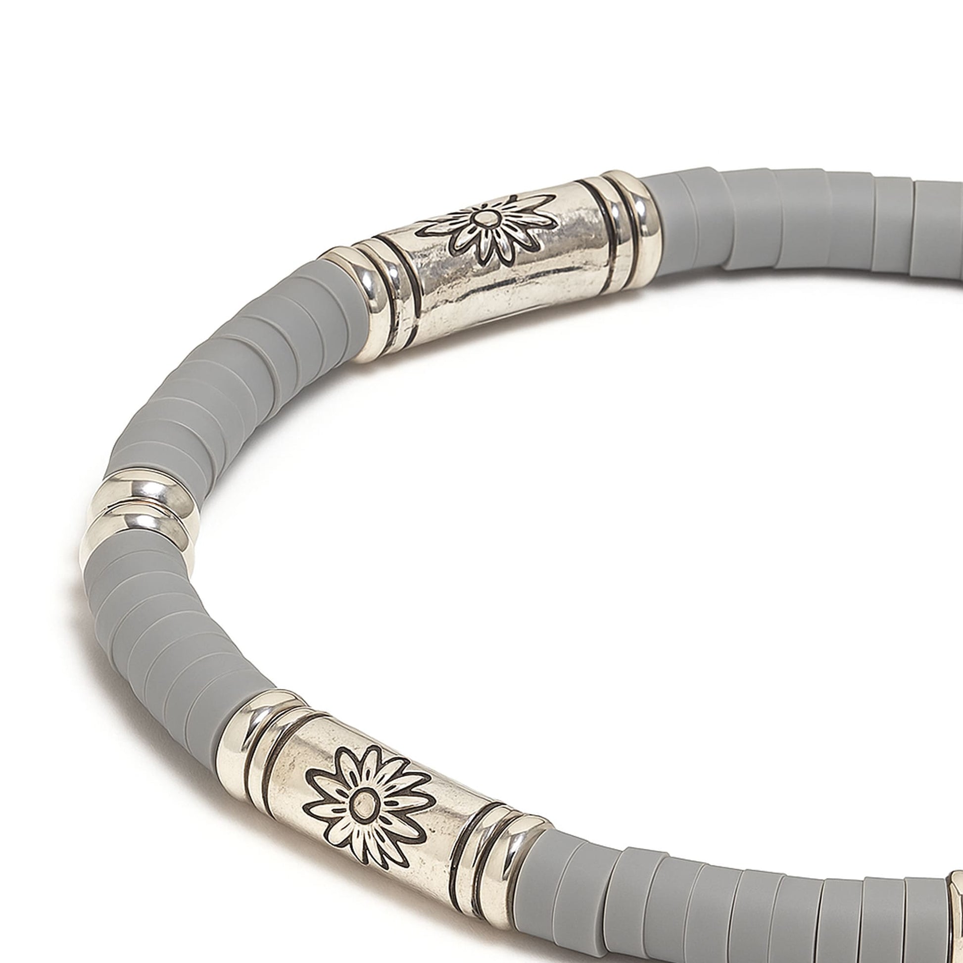 Macro view of gray bracelet showing engraved metal bead and gray clay discs