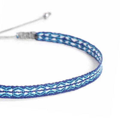 Close-up of Handmade Bracelet with blue woven band, turquoise wave pattern, and white stitching