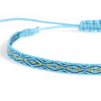 Detailed view of handmade rope bracelet texture with blue cord, navy pattern, and gold embroidery