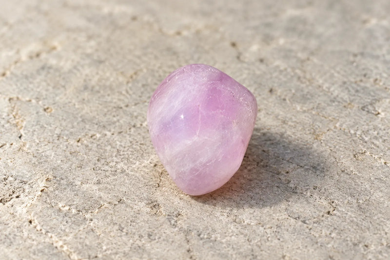 Rounded pale lilac-pink kunzite with cloudy internal markings.