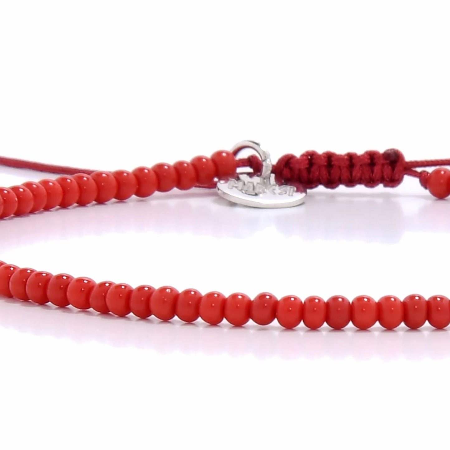 Detailed view of Men Beaded Bracelets with red seed beads with silver charm, seed bead texture, and cord knot