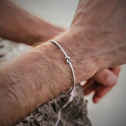 Men Silver Bracelet worn on wrist, showing slim polished band and knot centerpiece