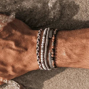 Men's beaded bracelets in colorful tones stacked on male wrist on a beach