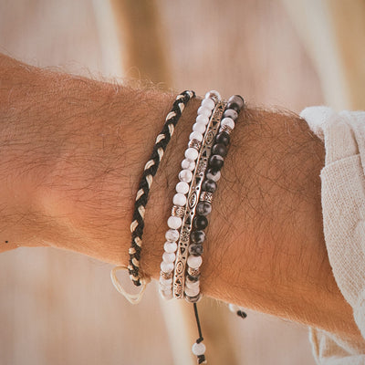 Side view of Palma silver bracelet set on wrist, showing braided cord and stacked beaded