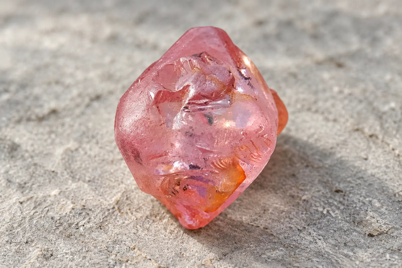Translucent pink spinel with an irregular outline and small warm-colored areas.