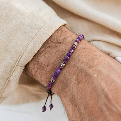 Purple Jasper Bracelet worn on a wrist with silver spacer beads, brown cord, and cream fabric sleeve.