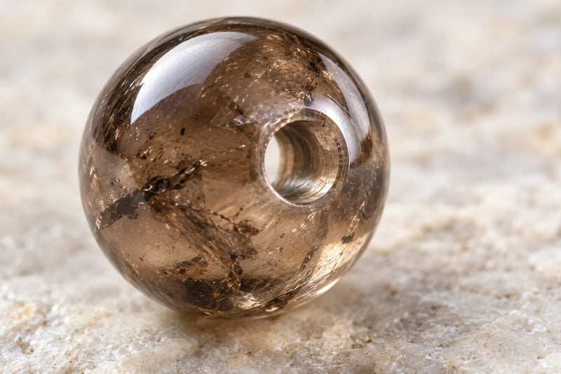 Polished smoky quartz bead for jewelry, showing its drilled hole, surface finish and internal inclusions.