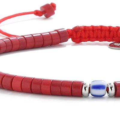 Detailed view of red gemstone jewelry with red clay beads with blue accent bead, Santorini clay bead texture, and cord knot