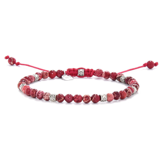 Red jasper bracelet with adjustable red cord and decorative silver spacers in a close-up side view.