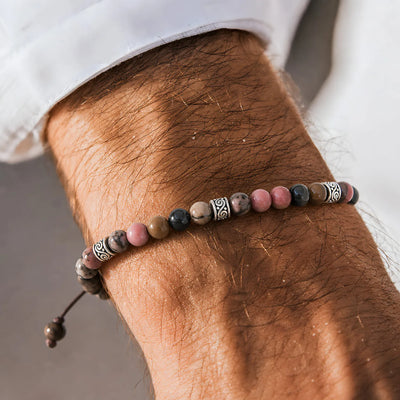 Rhodonite Bracelet worn on a wrist with beaded design and adjustable cord