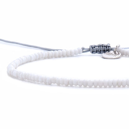 Close-up of Small Beaded Bracelets showing white seed beads with gray cord, silver charm, and cord closure