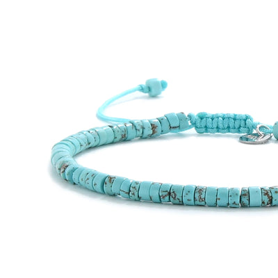 Close-up of turquoise beads showing turquoise clay beads with silver charm, silver charm, and cord closure