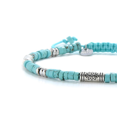 Close-up of Turquoise Jewelry for Sale showing turquoise clay beads with engraved silver spacers, silver charm, and cord