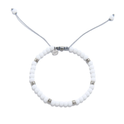 Top view of White Jade Bracelet with round white beads, silver spacers, gray cord, and charm.