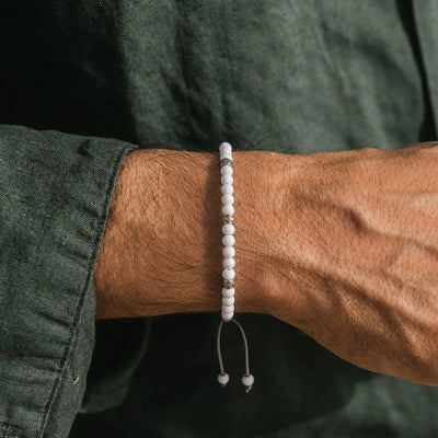 White Jade Bracelet worn on a wrist with white beads, silver accents, gray cord, and green sleeve.
