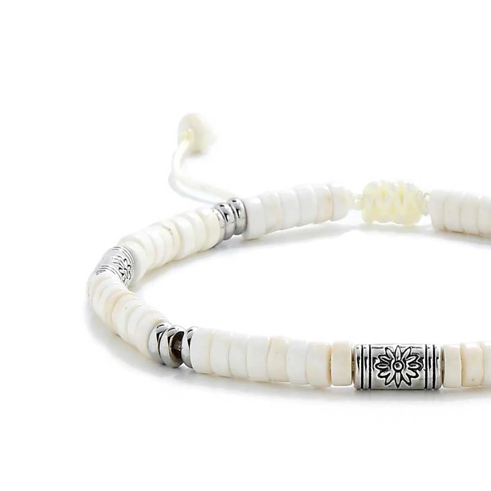 Close-up of White Stone Jewelry showing white clay beads with engraved silver spacers, silver charm, and cord closure