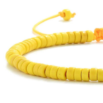 Detailed view of Yellow Bracelet with yellow clay beads with silver charm, clay bead texture, and cord knot
