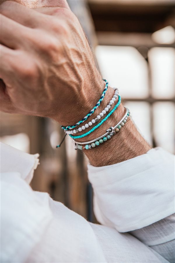 Layered turquoise and white bracelets worn on a wrist